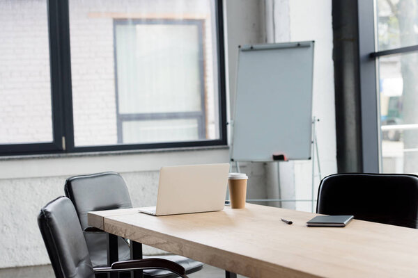 ноутбук и кофе пойдут на деревянный стол в современном офисе
