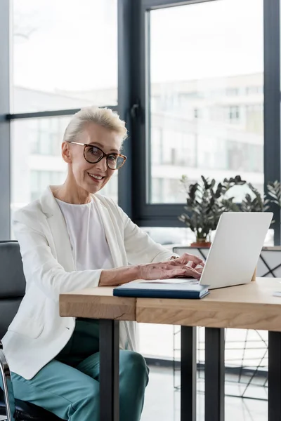 Cheerful Senior Businesswoman Eyeglasses Using Laptop Smiling Camera Office — Stock Photo, Image