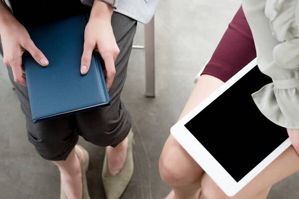 cropped image of businesswomen holding notebook and tablet in office