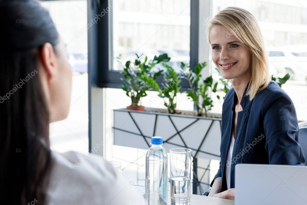 cropped shot of businesswomen talking and looking at each other in office