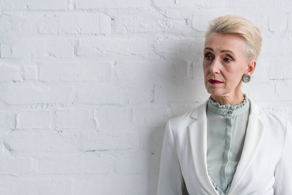 beautiful elegant senior businesswoman at white wall 