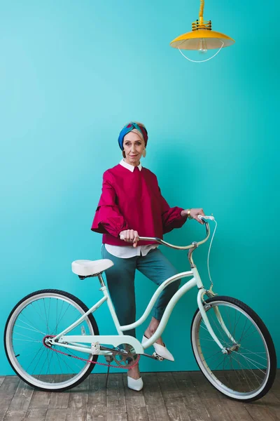 Модная Пожилая Женщина Позирует Велосипедом Возле Бирюзовой Стены — стоковое фото