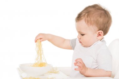 Beyaz arka plan üzerinde el ile spagetti yiyen sevimli küçük çocuk yan görünüm izole 