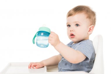 Bebek fincan su ile tutarak ve beyaz arka plan üzerinde izole sandalyesi otururken çok güzel küçük çocuk 