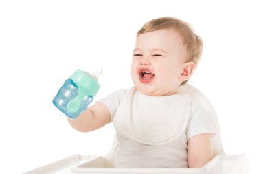 ağlayan çocuğu bebek Kupası holding ve beyaz arka plan üzerinde izole sandalyesi otururken önlük 