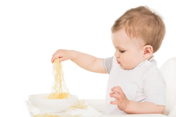 白い背景の分離された手でスパゲティを食べる愛らしい男の子の側面図 — ストック写真