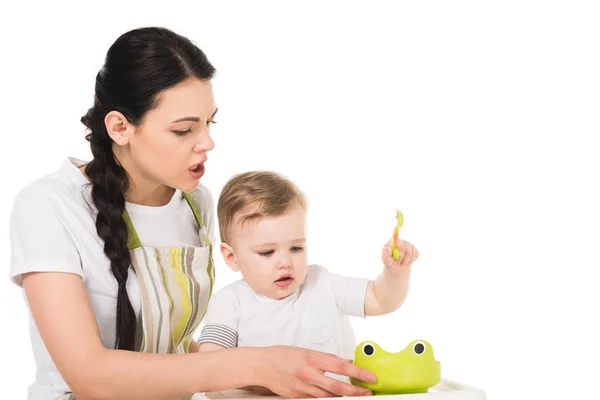 Angry Mother Apron Trying Feed Little Son Sitting Highchair Isolated — Stock Photo, Image