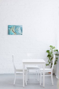 empty table in light cozy apartment with abstract painting on wall clipart