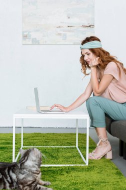 laptop süre evde yerde yatarken onu kedi ile çalışan güzel genç kadın yan görünüm
