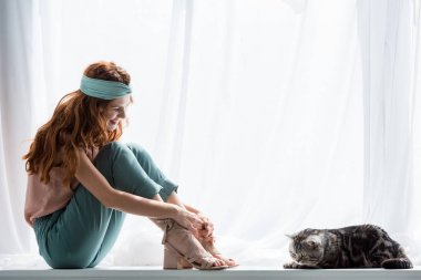 pencere ile tekir kedi üzerinde oturan çekici genç kadın