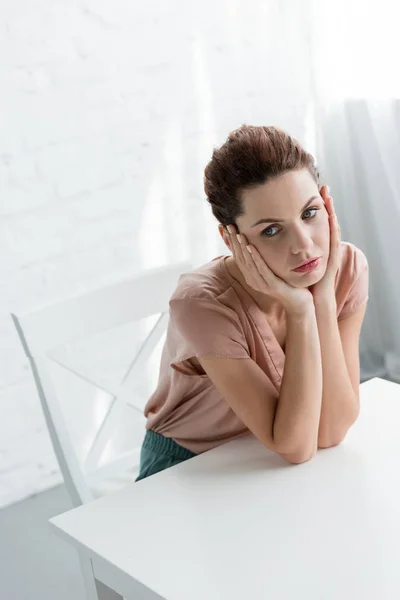 Depressed Young Woman Sitting Table Front White Brick Wall — Stock Photo, Image