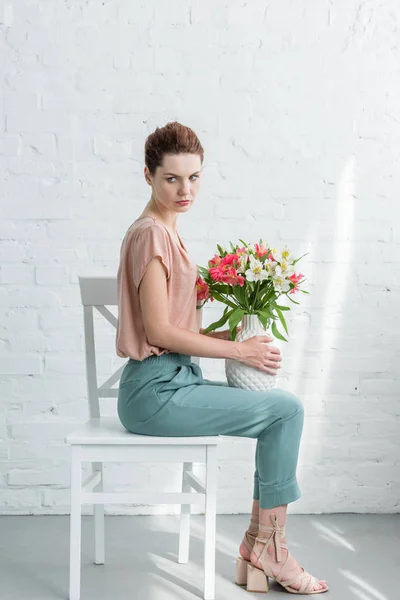 Vista Lateral Bela Jovem Segurando Vaso Com Flores Enquanto Sentado — Fotografia de Stock Grátis