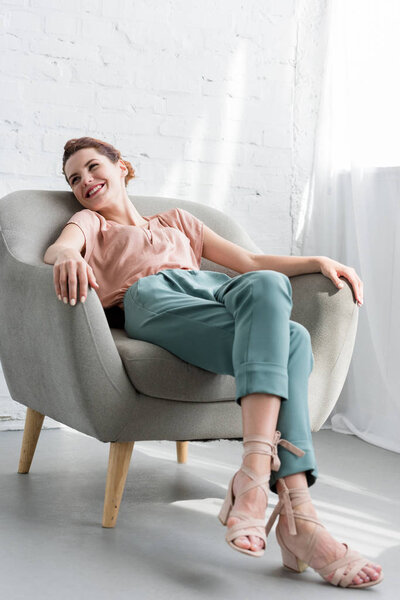 happy young woman relaxing on armchair at home