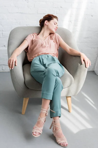 美しい若い女性自宅の肘掛け椅子でリラックス — ストック写真