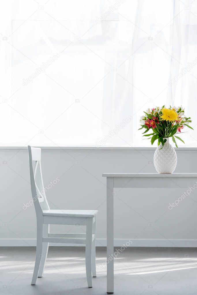vase with flowers on white table in light cozy apartment