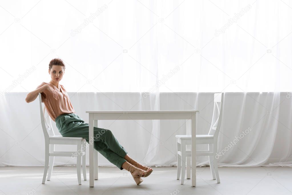 side view of lonely young woman sitting at table at home