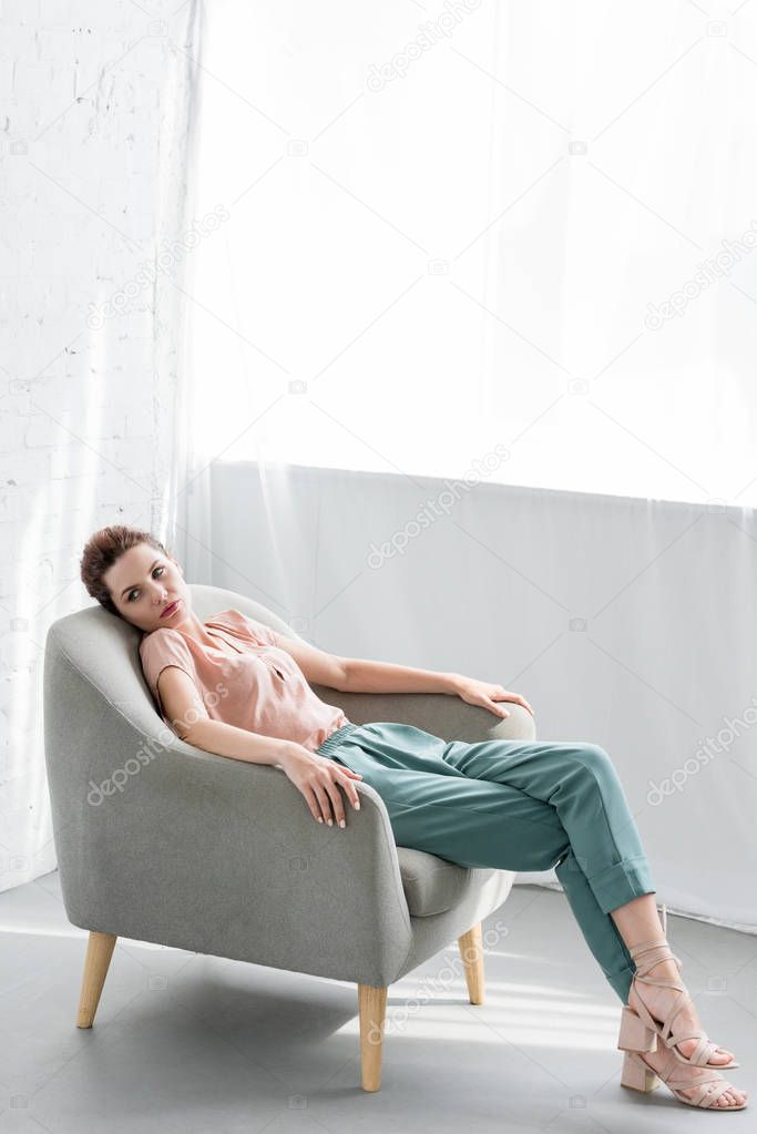 attractive young woman relaxing on armchair at home