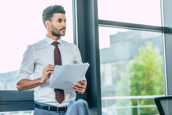 Serious Businessman Standing Window Holding Documents Looking Away — Stok fotoğraf