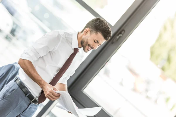 Νεαρός Επιχειρηματίας Χαμογελά Κοιτάζοντας Χαρτιά Στο Γραφείο — Φωτογραφία Αρχείου