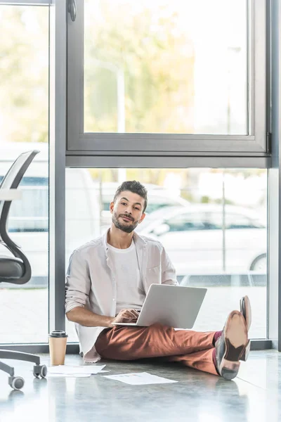 Mladý Podnikatel Ležérní Oblečení Sedí Podlaze Blízkosti Okna Pomocí Notebooku — Stock fotografie