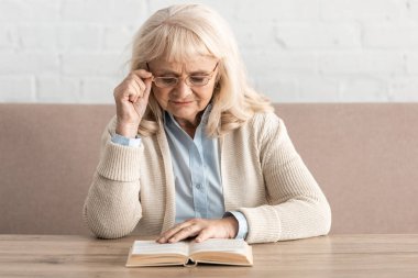 Alzheimer hastası son sınıf öğrencisi, kitap okuyor ve gözlük takıyor.