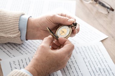 Gazetelerin yanında cep saati tutan kıdemli bir adam ve mektuplar. 