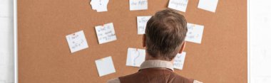 panoramic shot of sick senior man standing near board with papers  clipart