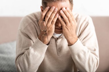 Alzheimer hastası, hayal kırıklığına uğramış yaşlı adam yüzünü kapatıyor. 