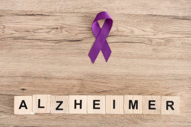 Alzheimer harfli tahta küplerin yanındaki mor kurdelenin üst görüntüsü. 