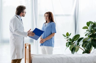 Beyaz önlüklü doktor hastanede çekici hemşireyle konuşuyor. 