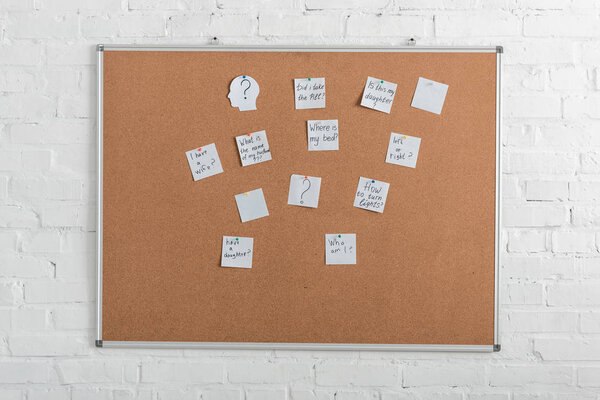 board with white papers with lettering near brick wall 