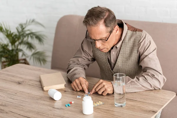 Hombre Jubilado Con Alzheimer Enfermedad Mirando Pastillas Mesa — Foto de Stock