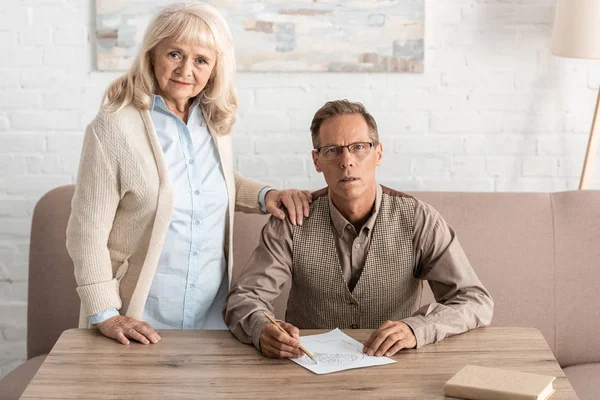 Seniorin Steht Neben Krankem Mann Und Zeichnet Auf Papier — Stockfoto