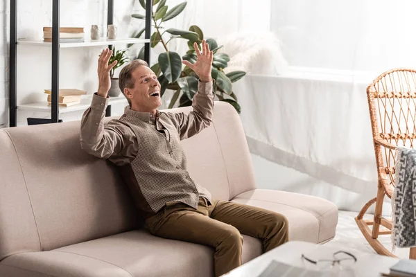 Cheerful Senior Man Sitting Sofa Gesturing Home — Stock Photo, Image