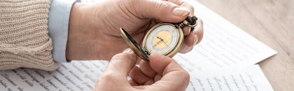 panoramic shot of senior man holding pocket watch near papers with letters 