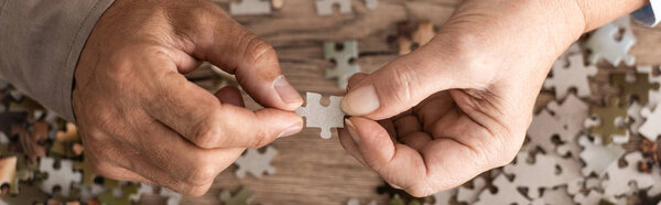 панорамный снимок супружеской пары, держащей в руках пазл
 