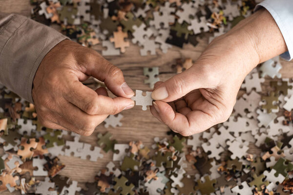 cropped view of retired couple holding jigsaw 