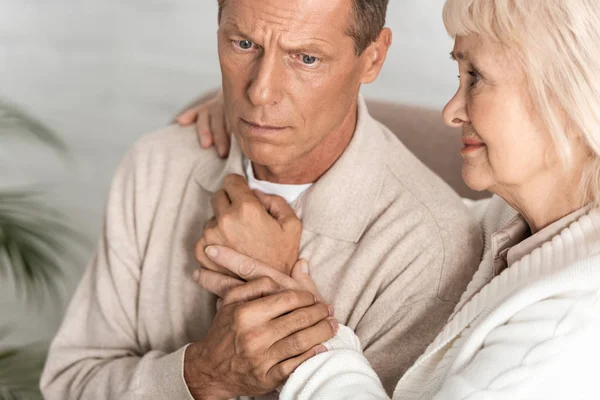 Sorgsen Pensionerad Kvinna Kramar Man Med Alzheimers Sjukdom Hemma — Stockfoto