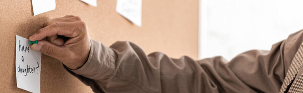 panoramic shot of retired man with alzheimer holding pin near papers on board 