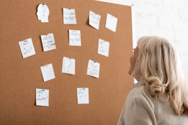 senior woman with dyslexia looking at board with papers 