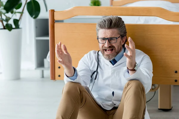 Beyaz Önlüklü Kızgın Doktor Yerde Oturuyor Hastanede Bağırıyor — Stok fotoğraf