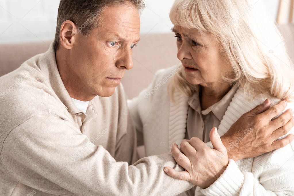 senior man with alzheimer disease sitting near worried wife  