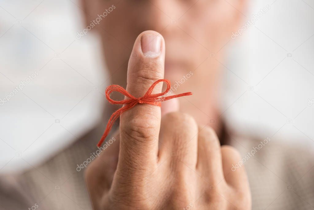 selective focus of senior man with alzheimers disease string human finger reminder