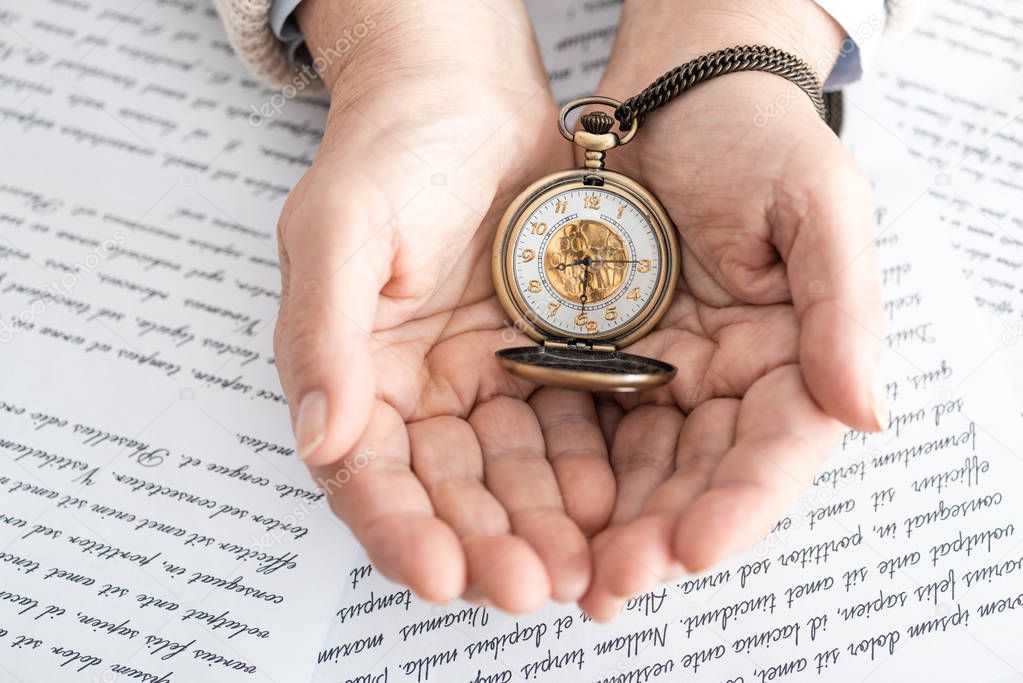 top view of senior woman holding pocket watch near papers with letters 