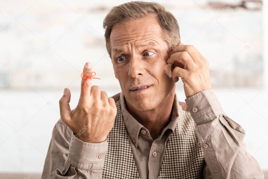 confused senior man looking alzheimers disease string human finger reminder 