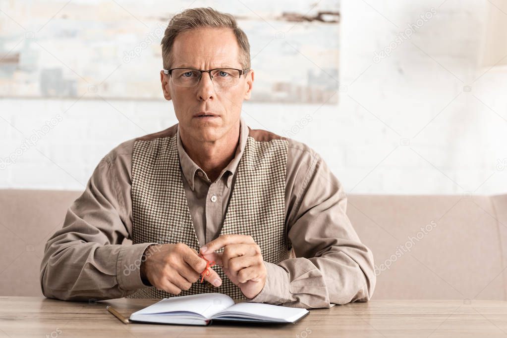 upset senior man with alzheimers disease string human finger reminder sitting near notebook 