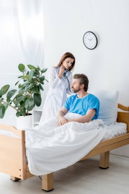 Beyaz önlüklü doktor hastanede steteskoplu hastayı muayene ediyor. 