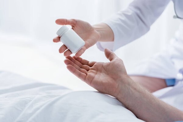 обрезанный вид врача, дающего бутылку с таблетками пациенту в больнице
 