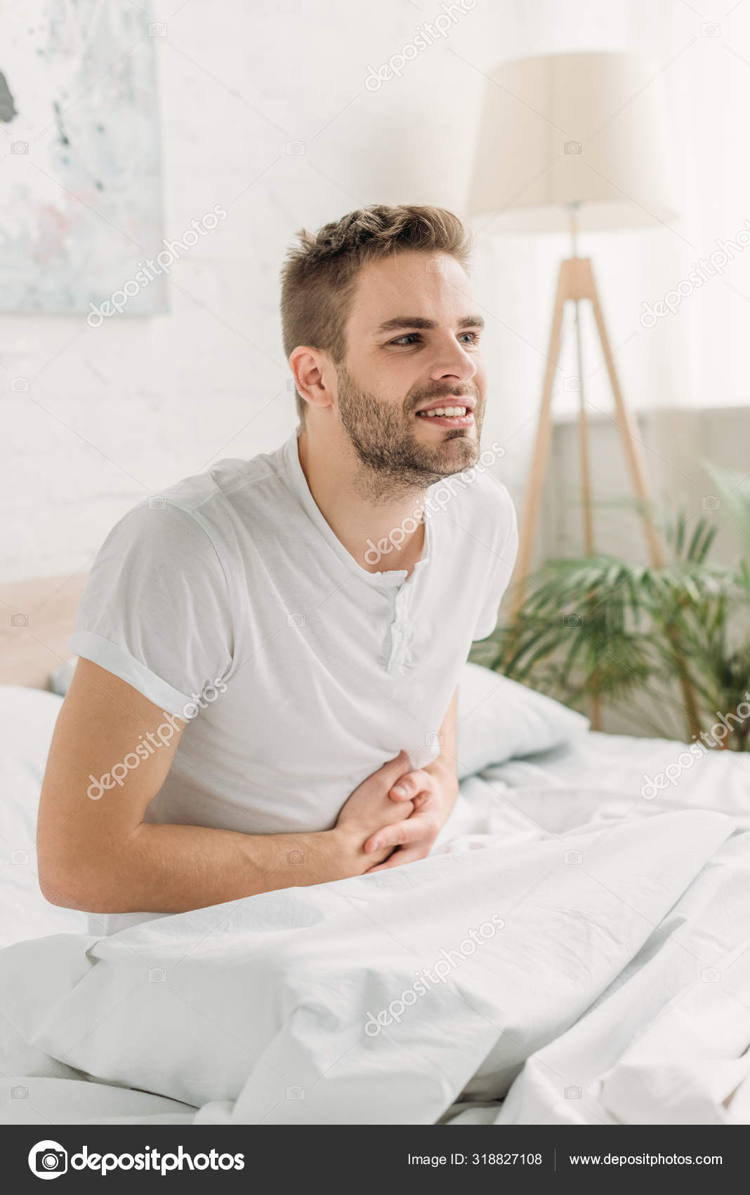 Young Man Sitting Bed Suffering Stomach Pain Stock Photo by