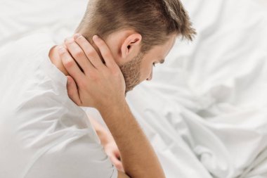 overhead view of young man suffering from neck pain clipart
